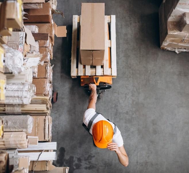 A worker moving a pallet of cartons inside a plant